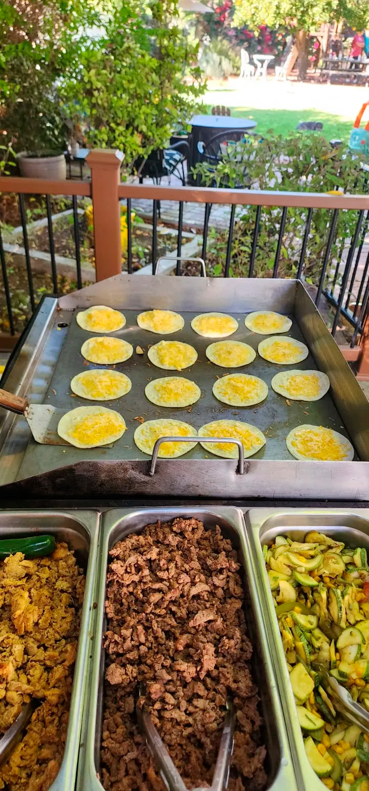 Tacolab LA live taco station during an event in Los Angeles. Fresh corn tortillas cooking on the grill with melted cheese, carne asada, chicken and grilled vegetables for our catering service.