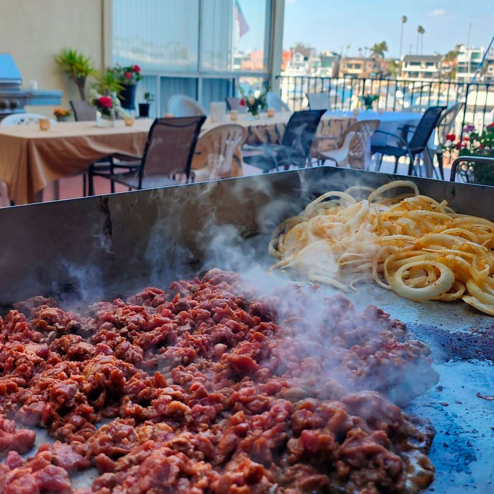 relax-atmosphere Tacolab LA live grill catering in Los Angeles. Fresh carne asada and onions sizzling on the flat top with ocean view for events.