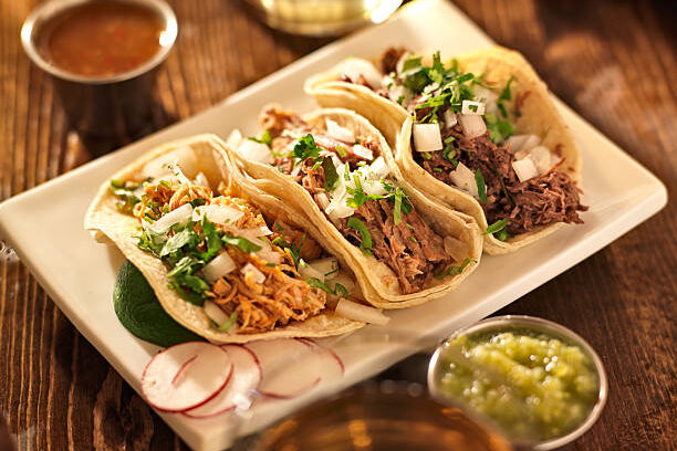 Tacolab LA authentic carnitas tacos for catering in Los Angeles. Tender slow-cooked pork tacos with chopped onion, fresh cilantro, radishes, and salsas on corn tortillas.